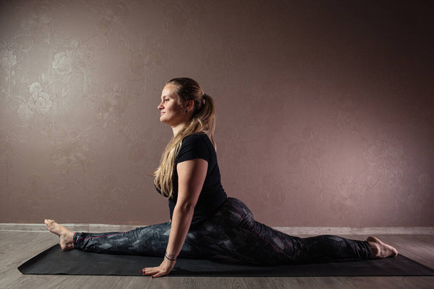 Genç sportif çekici kadın yoga yapıyor, yoga pozisyonunda meditasyon yapıyor spor kıyafetleri giyiyor, kapalı alanda yoga yapıyor, kahverengi yoga stüdyosu. - Fotoğraf, Görsel