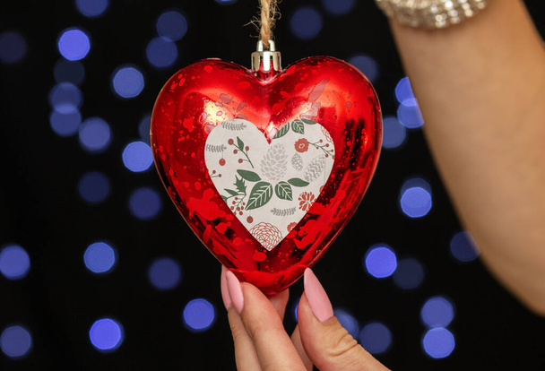 γυναικεία χέρια που κρατούν ένα χριστουγεννιάτικο παιχνίδι σε σχήμα καρδιάς - Φωτογραφία, εικόνα