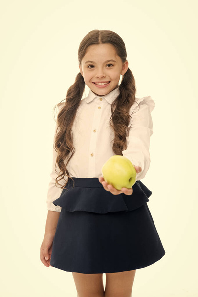 Girl cute pupil hold apple fruit stand on white background. Kid happy hold apple. School snack concept. Healthy nutrition diet. Apple vitamin snack. Child schoolgirl wear formal uniform hold apple - Photo, Image