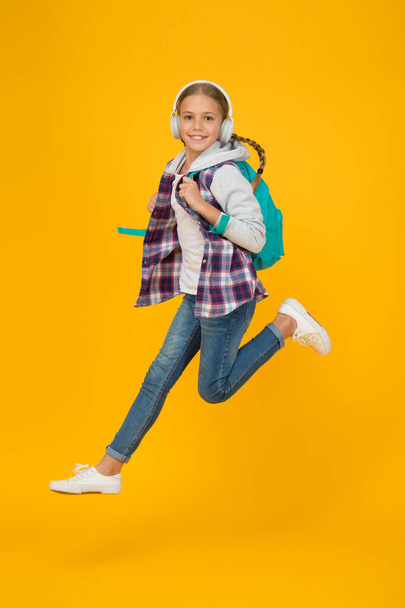 Always in motion. Energetic cheerful teen listening music. Stylish schoolgirl going to school. Girl little fashionable girl carry backpack. School daily life. Happy carefree child. School and leisure - Photo, image