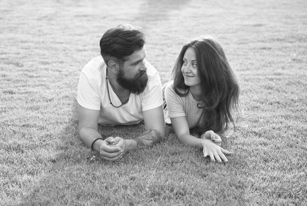 Relaxed and in love. Couple relaxing on grass enjoying each other. Man bearded hipster and pretty woman in love. Summer vacation. Fall in love. Summertime happiness. Happy together. Couple in love - Foto, afbeelding