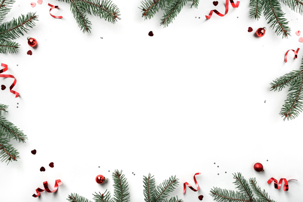 Kreatywna rama wykonana z gałązek jodły bożonarodzeniowej na białym tle z czerwoną dekoracją, szyszki sosnowe. Kartka świąteczna i noworoczna, ferie zimowe. Płaskie ułożenie, widok z góry - Zdjęcie, obraz