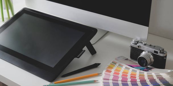 Professzionális tervezői munkaterület kivágott képe digitális táblagéppel, asztali számítógéppel és színes mintákkal  - Fotó, kép