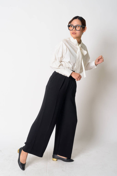 Portrait of stressed Asian businesswoman with eyeglasses running away - Foto, Imagen