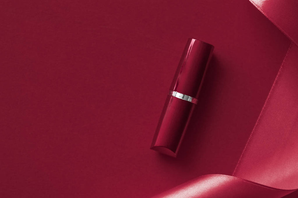 Luxury lipstick and silk ribbon on maroon holiday background, ma - Zdjęcie, obraz