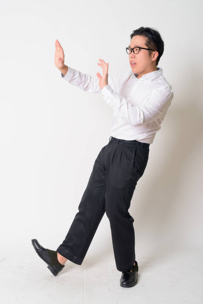 Portrait of stressed young Asian businessman with eyeglasses running away - Foto, Imagem