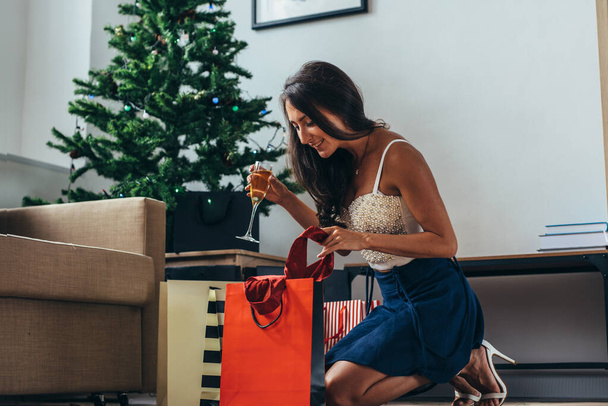 Fiatal nő a karácsonyfa közelében bevásárló szatyrok. - Fotó, kép