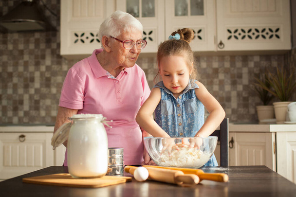 Aranyos kislány és a nagymamája főzés a konyhában. - Fotó, kép