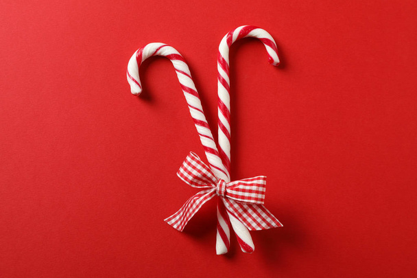 Sweet candy canes with bow on red background, space for text - Foto, Bild
