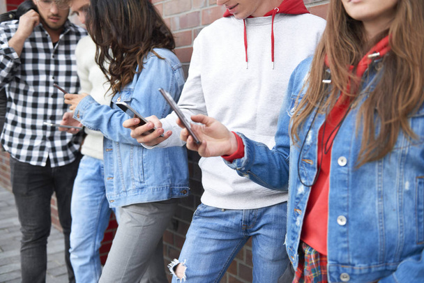 Group of young people with smart phones in a row  - 写真・画像