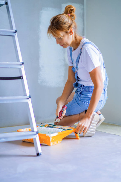 young beautiful woman makes repairs in the apartment, paints the walls with a roller. Molar work. - Foto, imagen