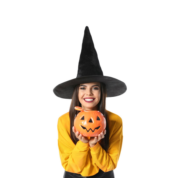 Beautiful woman wearing witch costume with Jack O'Lantern candy container for Halloween party on white background - Fotó, kép