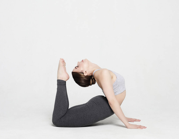 Young woman practicing yoga, working out, wearing sportswear, studio shoot over white background - Fotó, kép