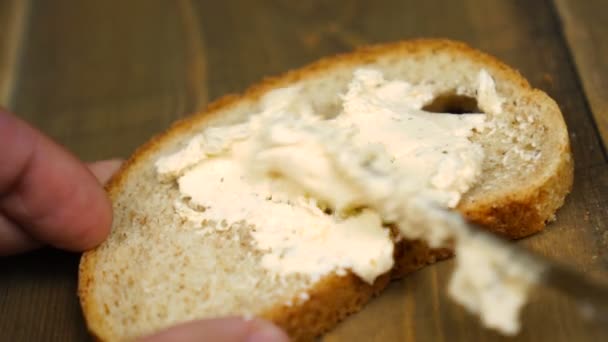 Man makes a peanut butter sandwich.. Closeup of male hands spreading butter on bread in kitchen - 映像、動画