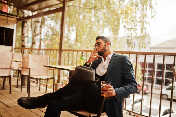 Handsome well-dressed arabian man smoke cigar with glass of whis - Photo, Image