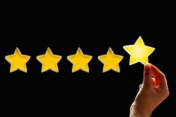 Een vrouw geeft een vijfde ster rating, het concept van een positieve rating, beoordelingen en feedback op zwarte achtergrond. - Foto, afbeelding