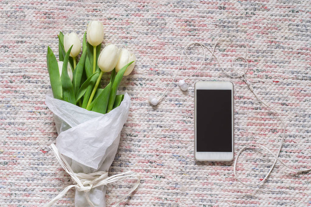 Bouquet of white tulips and phone with headphones - 写真・画像
