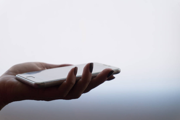 Female hands holding a smartphone on light gradient background - Фото, зображення