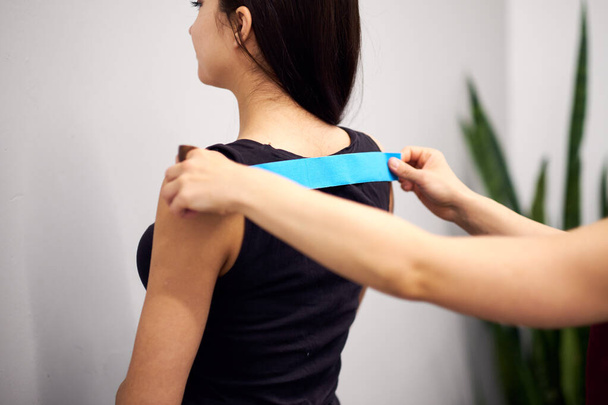 kinesiology taping treatment with blue tape on female patient injured arm. Sports injury kinesio treatment - Φωτογραφία, εικόνα