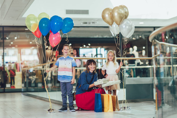 Jonge moeder met kinderen hebben plezier in winkelcentrum. - Foto, afbeelding