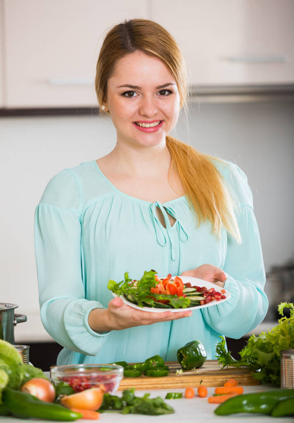 Happy girl holding plate with salad in home kitchen - Fotoğraf, Görsel