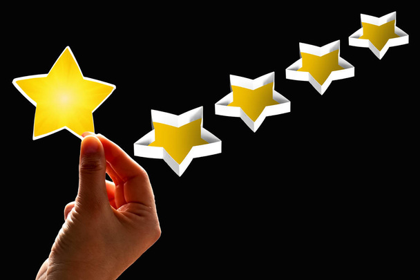 Een vrouw beschouwt (geeft) een eerste ster rating, het concept van een positieve rating, beoordelingen en feedback op zwarte achtergrond. - Foto, afbeelding