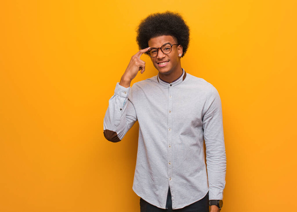 Νεαρός Αφροαμερικάνος πάνω από έναν πορτοκαλί τοίχο κάνει μια χειρονομία απογοήτευσης με το δάχτυλο - Φωτογραφία, εικόνα