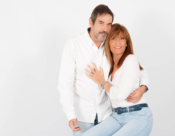Un couple adulte de 50 ans pose dans un studio photographique d'une manière joyeuse avec un fond blanc
. - Photo, image