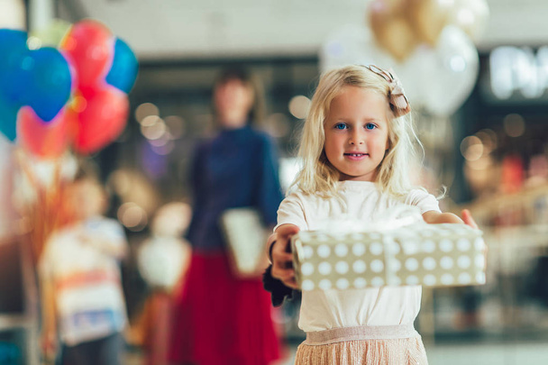 Pieni tyttö tilalla lahja ostoskeskuksessa, hauskaa famil
 - Valokuva, kuva