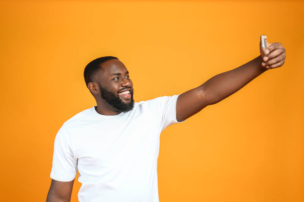 Happy African-American man taking selfie on color background - Photo, Image