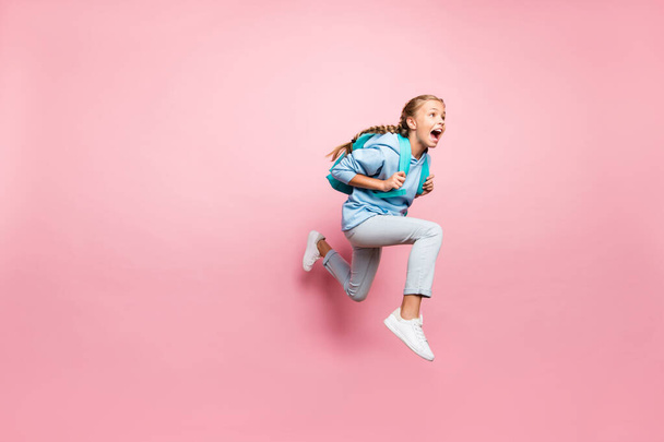 Full length body size turned photo of frightened fearful girl running away in fear with backpack behind wearing blue sporty wear sweatshirt jeand denim hoodie isolated over pink pastel color - Fotó, kép