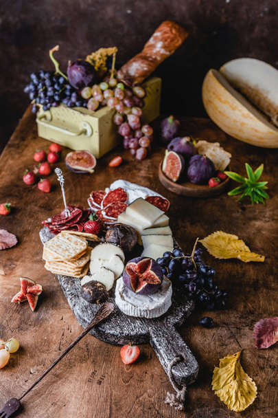 assortment of cheese with figs and grapes with ham and crackers on shabby background, top view - Foto, Imagem
