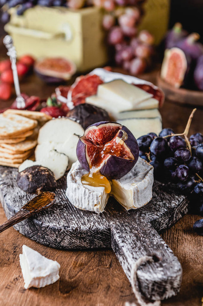 assortment of cheese with figs and grapes with ham and crackers on shabby background, top view - Valokuva, kuva
