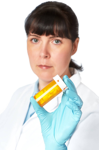 Female doctor or nurse with yellow jar of pills in gloved hand - Valokuva, kuva