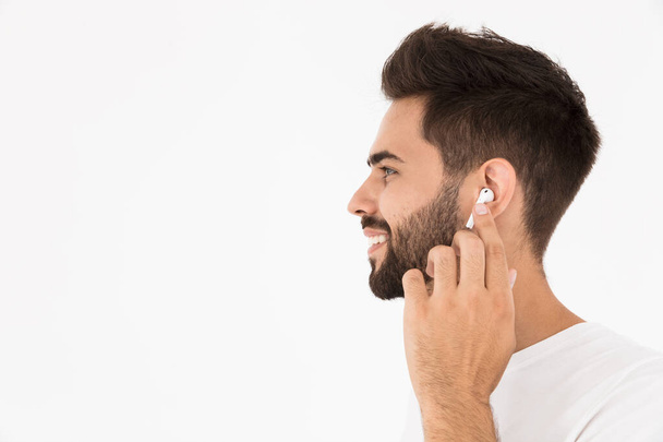 Image closeup of unshaven smiling man listening music with earpod - Foto, afbeelding