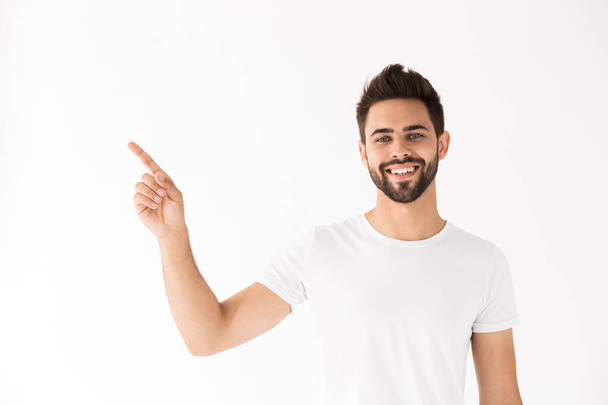 Image of attractive smiling man looking at camera and pointing finger aside at copyspace - Fotoğraf, Görsel