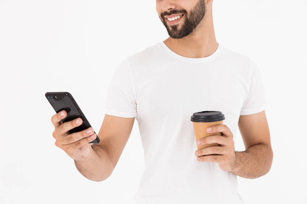 Image cropped of handsome joyful man drinking coffee takeaway and using cellphone - Foto, immagini