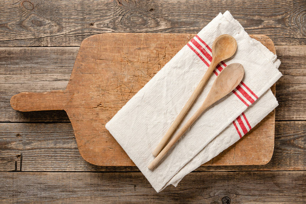 Vintage wooden cutting board, spoons and kitchen towel on wooden - 写真・画像