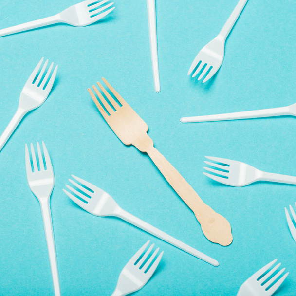Pratos ecológicos, garfos de madeira e plástico sobre fundo azul
 - Foto, Imagem