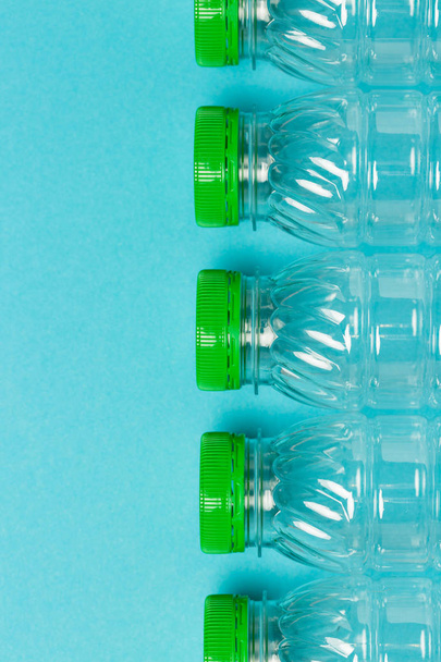 Пластиковые бутылки с зелеными колпачками на голубом фоне
 - Фото, изображение
