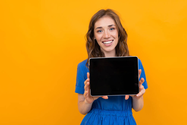 Frau im Kleid posiert mit digitalem Tablet vor orangefarbenem Hintergrund   - Foto, Bild