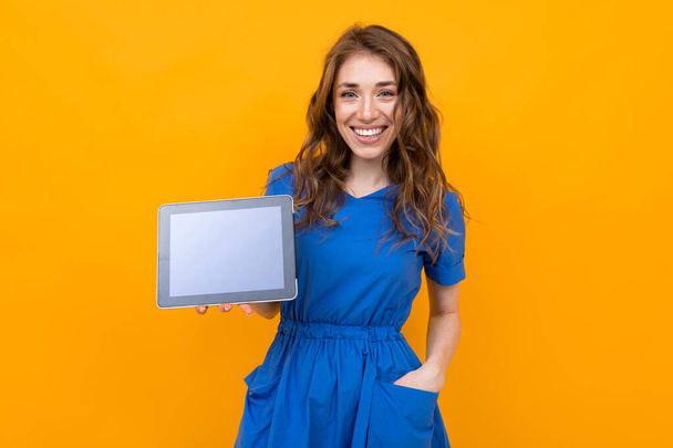 Woman in dress posing with digital tablet against orange background   - Foto, Imagem