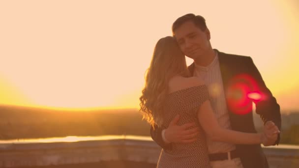 Twee geliefden dansen samen op het dak bij zonsondergang in het zonlicht - Video