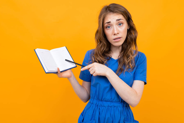 Woman in dress posing with notebook against orange background  - Foto, Bild