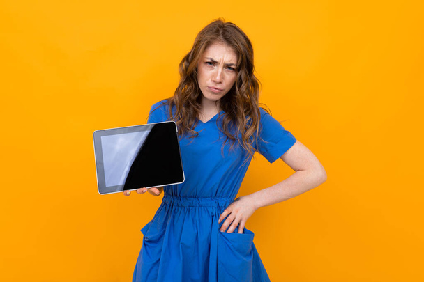 Woman in dress posing with digital tablet against orange background   - Foto, Imagen