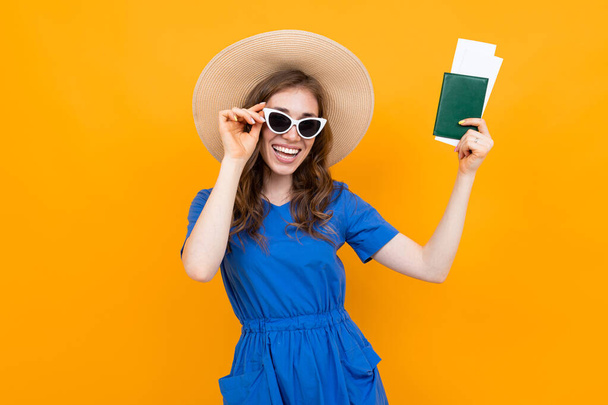 Woman in dress posing with passport against orange background  - Fotó, kép