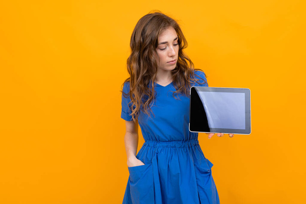 女性で服を着てオレンジの背景にデジタルタブレットでポーズ   - 写真・画像