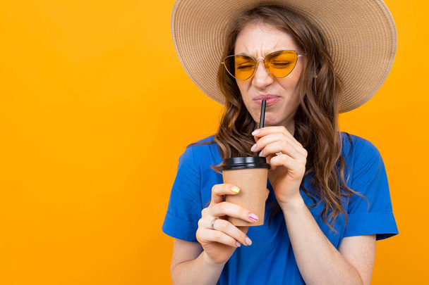 Woman in dress posing with beverage against orange background  - 写真・画像