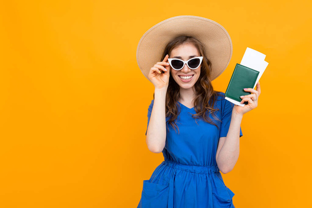 Mulher de vestido posando com passaporte contra fundo laranja
  - Foto, Imagem