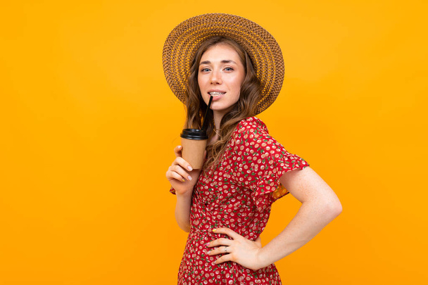 woman in red dress with print and straw hat with coffee - Foto, Imagem